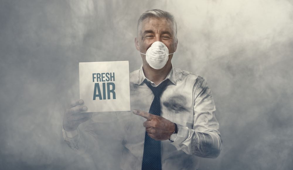 man with a mask holding "fresh air" sign